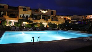 A swimming pool with lounge chairs and a wooden bridge.