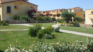 A residential building with a stone wall, a paved walkway, and a well-maintained lawn.