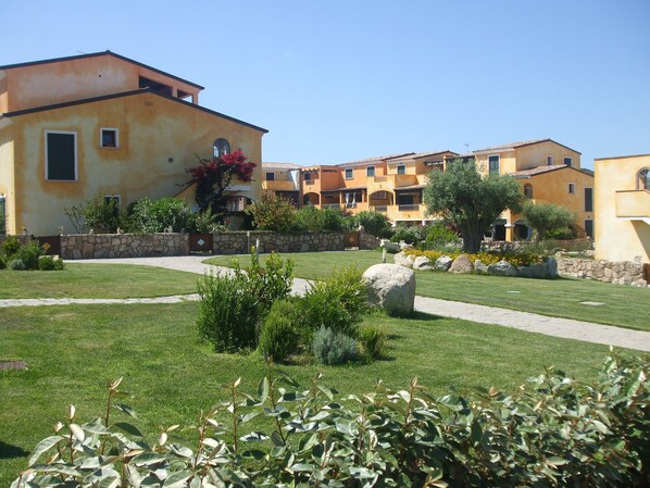 A residential building with a stone wall, a paved walkway, and a well-maintained lawn. - SPECIAL OFFER SUMMER SANTA TERESA GALLURA ELEGANTE RESIDENCE ALL INCLUSIV (Santa Teresa di Gallura)