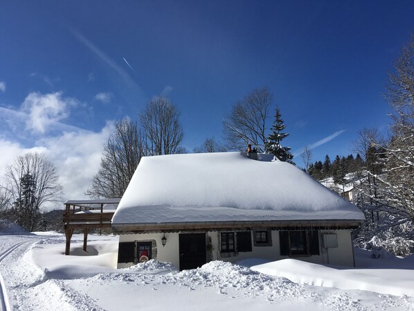 A snow-covered building with a wooden deck, a small porch, and a snow-covered roof. - Get back to basics in a chalet-style gîte for 6 to 15 people (Gérardmer)