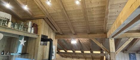 Un interior rústico de madera con una mesa de comedor, sillas, un sofá y una chimenea.