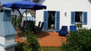 A house with a wooden deck, outdoor seating, and a blue umbrella. - thatched roof house at the sea, pets welcome, fenced (Mecklemburg-Vorpommern)