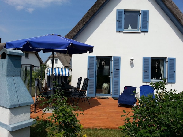A house with a wooden deck, outdoor seating, and a blue umbrella. - thatched roof house at the sea, pets welcome, fenced (Mecklemburg-Vorpommern)