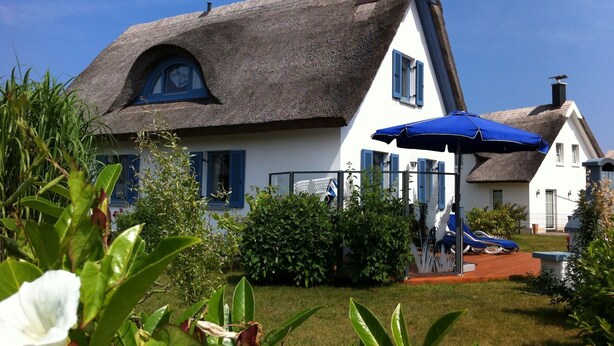 A traditional house with a thatched roof, a small garden, and a blue umbrella. - thatched roof house at the sea, pets welcome, fenced (Mecklemburg-Vorpommern)