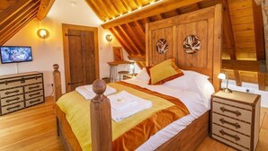 Ein gemütliches Schlafzimmer mit Holzboden, einem Bett mit Holz-Kopfteil, einem Nachttisch und einer Kommode.