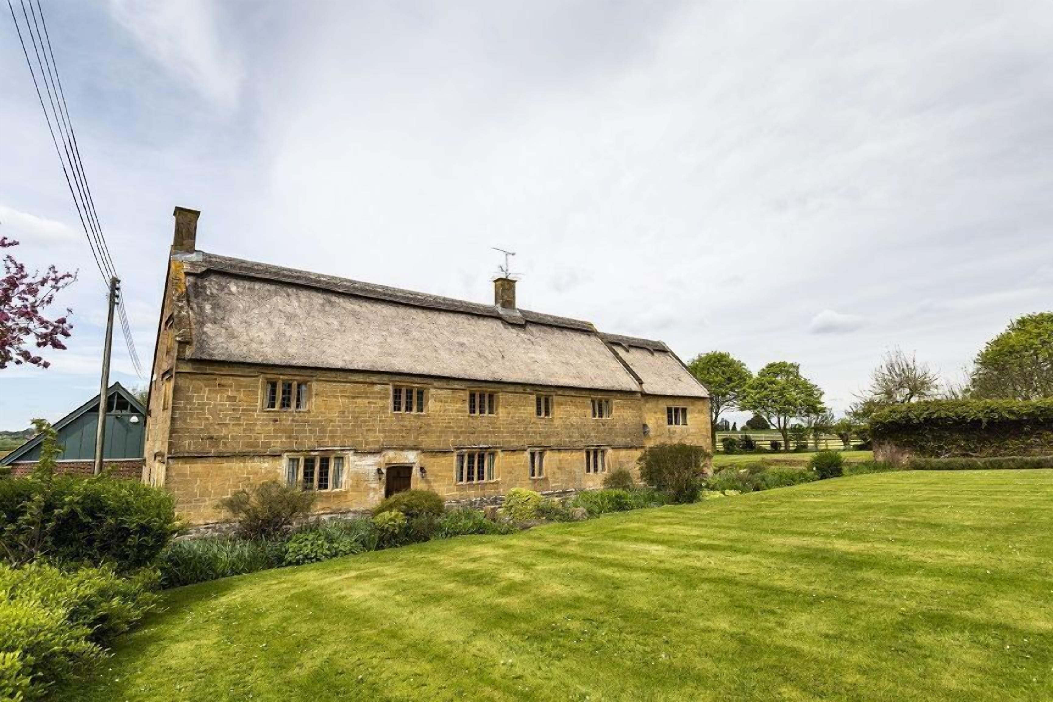 A stone farmhouse with a large lawn in front.