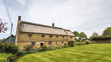 A stone farmhouse with a large lawn in front.