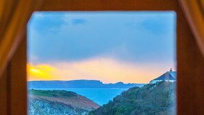 A coastal landscape with a building on a hill, overlooking the sea. - Luxury House With Magnificent Sea Views (Tintagel)