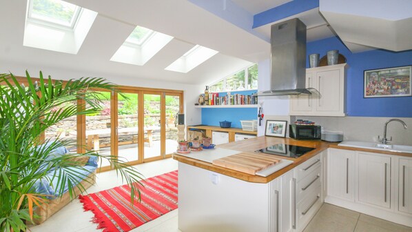A modern kitchen with skylights, a central island, and a view of the garden. - Luxury House With Magnificent Sea Views (Tintagel)