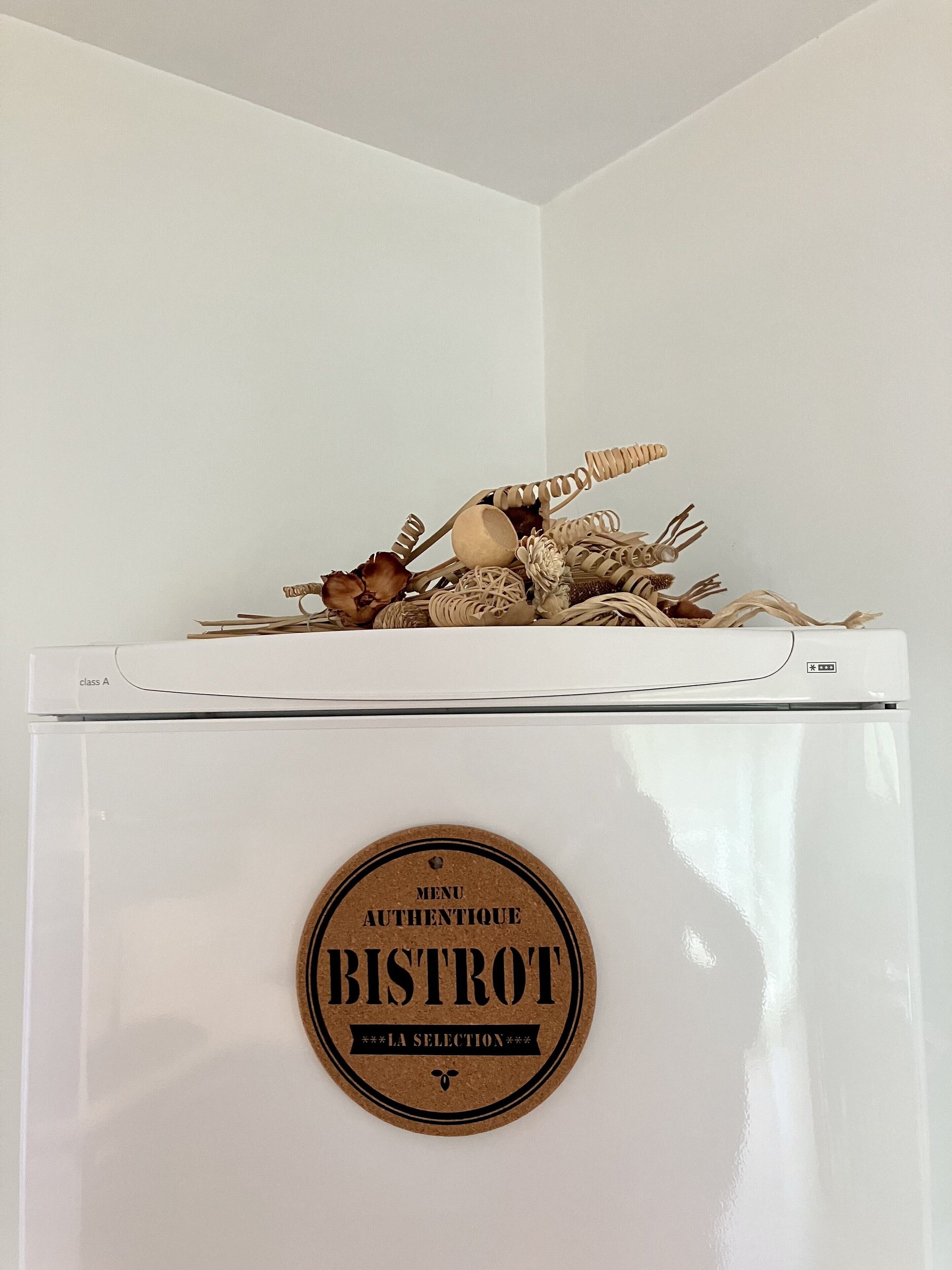 A white refrigerator with a cork label that reads 'BISTROT LA SELECTION' on its front.
