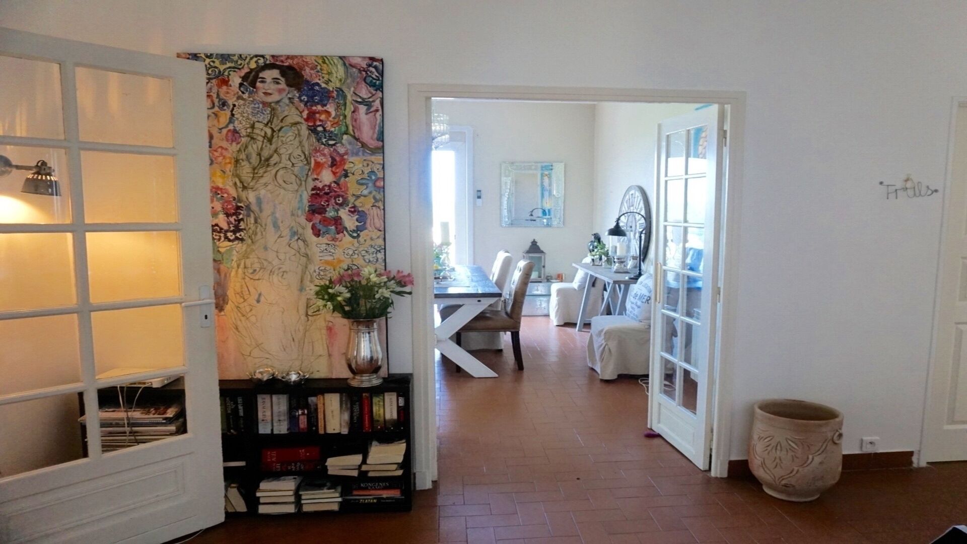 Ein Flur mit Bücherregal, einem Essbereich und einer Tür zu einem anderen Zimmer.