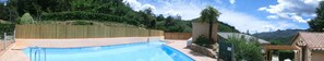 Piscina com cerca de madeira, pérgola e vista para montanhas.