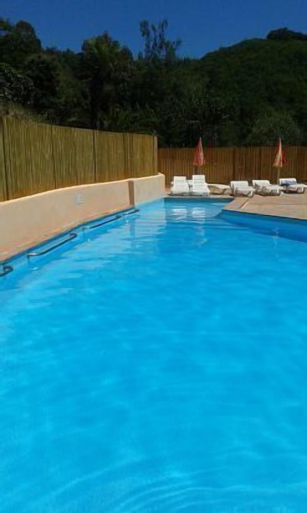 A clear blue swimming pool with lounge chairs and umbrellas.
