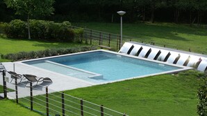Una piscina rectangular con un borde pavimentado y una valla.