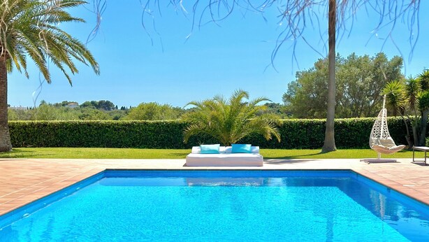 Una piscina rettangolare con acqua cristallina, circondata da un solarium piastrellato.
