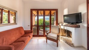 Ein Wohnzimmer mit einer Couch, einem Sessel, einem Kamin und einem Fernseher.