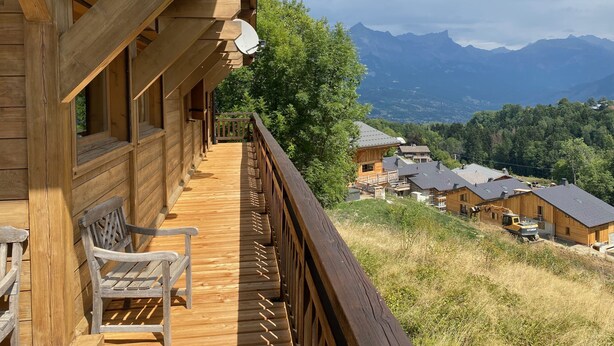 A wooden cabin with a balcony overlooking a mountainous landscape. - Huge Chalet in Combloux, sleeps up to 14, 5mins access to huge Evasion ski area. (Combloux)