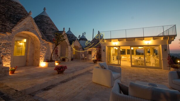 A stone building with a balcony and outdoor seating area.