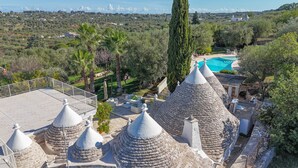 A villa with multiple conical roofs, a swimming pool, and a view of the surrounding landscape.