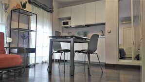 A modern kitchen with white cabinets, a microwave, and a dining table with chairs.