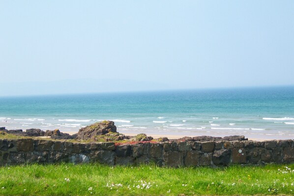 A coastal view with a stone wall and grassy foreground leading to the sea. - Sea front Apartment In Castlerock, With Stunning Panoramic Views (Castlerock)