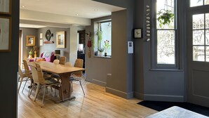 Un comedor con una mesa y sillas de madera, una cocina con ventanal y una puerta con vistas al exterior.