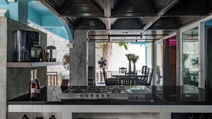 Una cocina moderna con estufa a gas, cafetera y una botella de vino.