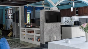 Una cocina moderna con televisor de pantalla plana, armarios de madera y una isla de mármol.