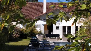 Ein Haus mit Ziegeldach, Swimmingpool und Gartenmöbeln.
