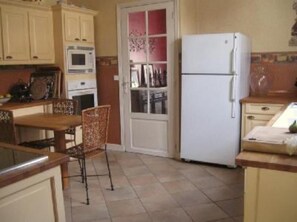 Enjoy meals at the dining table with two chairs, microwave, and refrigerator in this compact kitchen.