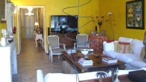 Ein Wohnzimmer mit gelber Wand, einem weißen Sofa, einem Couchtisch und einem Fernseher.