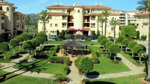 Ein mehrstöckiges Hotel mit Innenhof, Palmen und einem Pavillon.