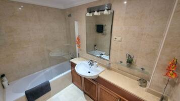 A modern bathroom with a bathtub, a sink, a mirror, and a shower.