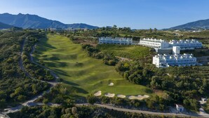 Ein Golfplatz mit einem Hotelkomplex im Hintergrund.