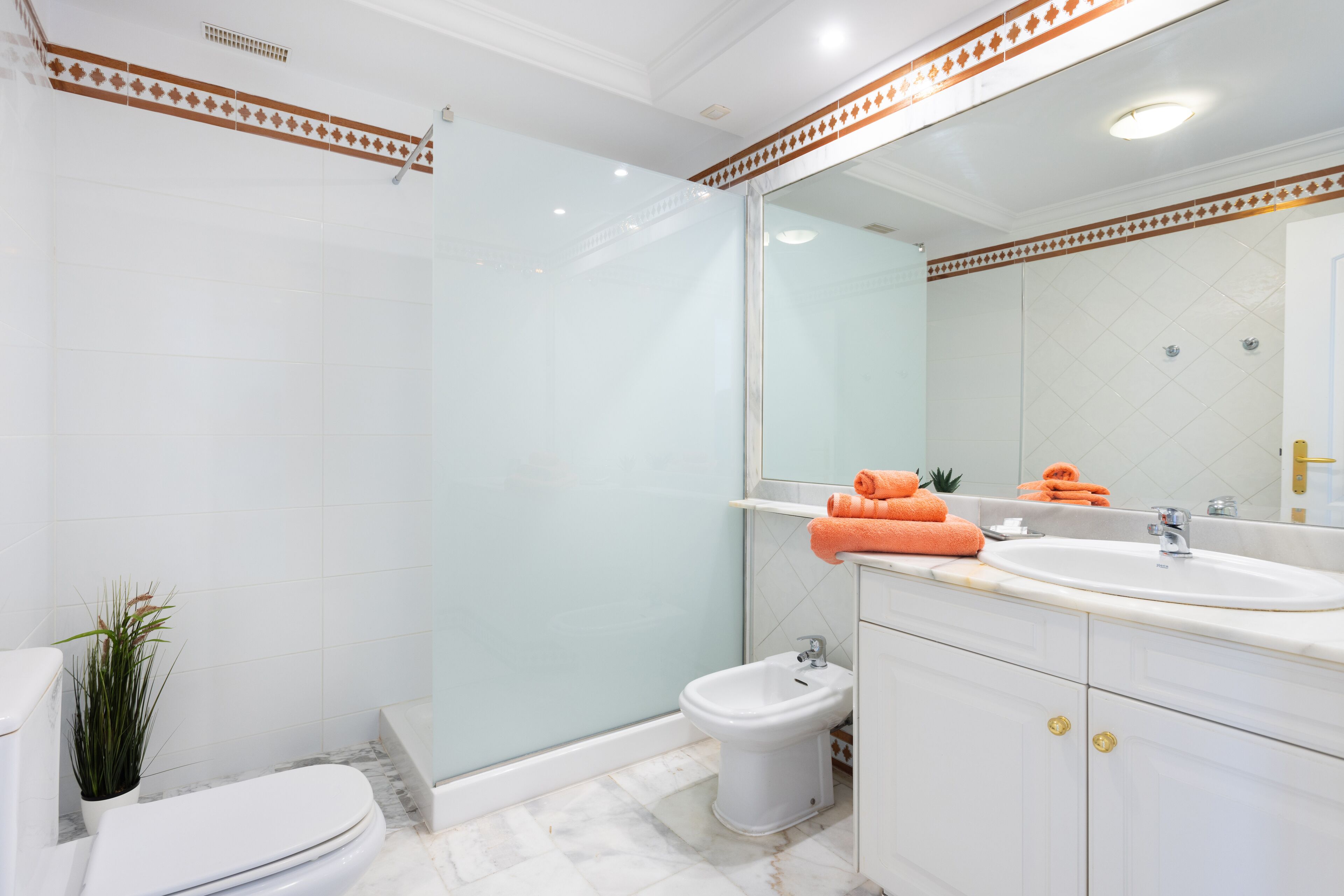 Une salle de bain équipée de toilettes, d’un bidet et d’un grand miroir au-dessus du lavabo.
