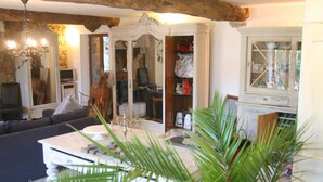 A living room with a sofa, a table, a chandelier, and a cabinet. - Luxurious Gite in tranquil surroundings with private heated salt water pool (Louvigne-Du-Desert)