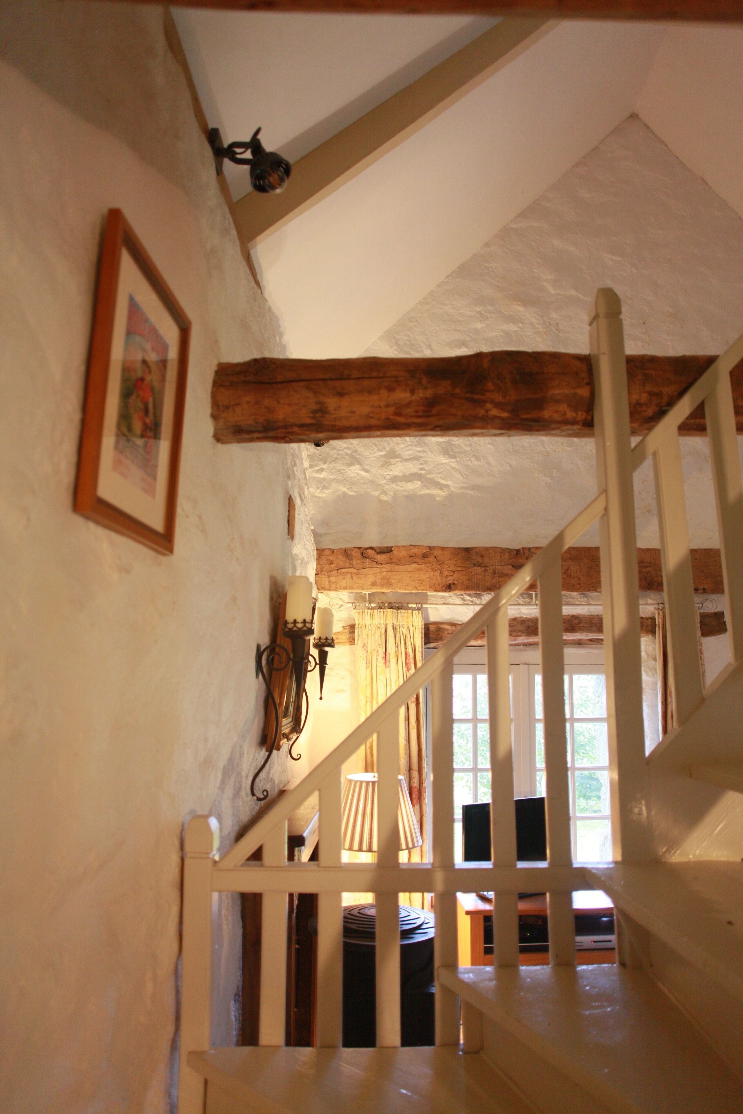 A wooden staircase with white railings leading to a room with a window.