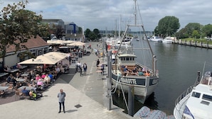Un port de plaisance avec des bateaux amarrés, des espaces de détente en plein air et une promenade piétonne.