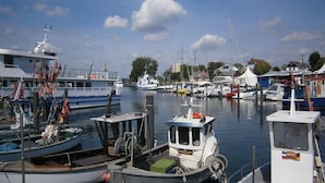 Un port de plaisance où sont amarrés divers bateaux, un petit bateau portant l’inscription « NIE 103 » sur son flanc, et un bateau blanc portant l’inscription « HELENE » sur son flanc.