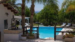 A pool area with a view of the ocean, surrounded by palm trees and lounge chairs. - House / Villa - Avola (Avola)