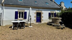 Une maison à deux étages avec une terrasse en gravier, un barbecue et une antenne parabolique.