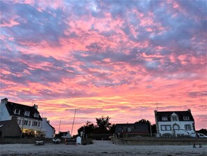 Un bâtiment situé sur la côte, avec une enseigne indiquant « BAR CRÊPERIE », et une plage au premier plan.