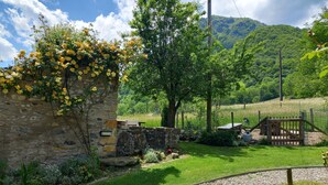 A stone building with a garden path, a wooden gate, and a view of a green hillside. - With Stunning Views, A Great Location For Mountain Activities And Relaxing (Campan)