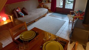 A cozy living room with a sofa, a dining table set with plates, glasses, and cutlery, and a television on a stand. - With Stunning Views, A Great Location For Mountain Activities And Relaxing (Campan)