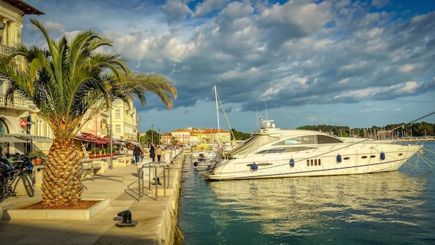 A waterfront marina with a large yacht docked, palm trees, and buildings with outdoor seating. - Private, fully fenced and pet-friendly pool villa near the sea (Labin)