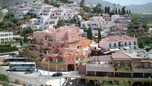 A hillside town with white and pink buildings, a bus, and mountains in the background. - Modern, Spacious, and Well Equipped Apartment With Mountain And Sea Views (Nerja)