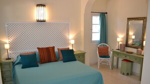 Un dormitorio con cama, mesitas de noche, una silla, cómoda y espejo.