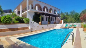 Una piscina con una casa blanca al fondo.