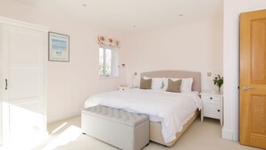 A bedroom with a bed, nightstands, a window, and a door.