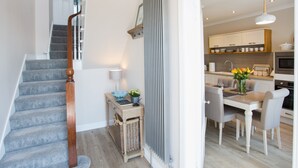Uma cozinha moderna com área de refeições, uma escada e uma pequena mesa com luminária e flores.
